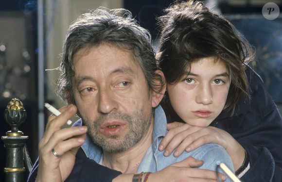 En France, à Paris, en mai 1985, Serge Gainsbourg chez lui avec sa fille Charlotte dans son hôtel particulier de la rue de Verneuil, posant au milieu de son bric-à-brac où il entasse des objets hétéroclites (Archives). © Michel Marizy via Bestimage
