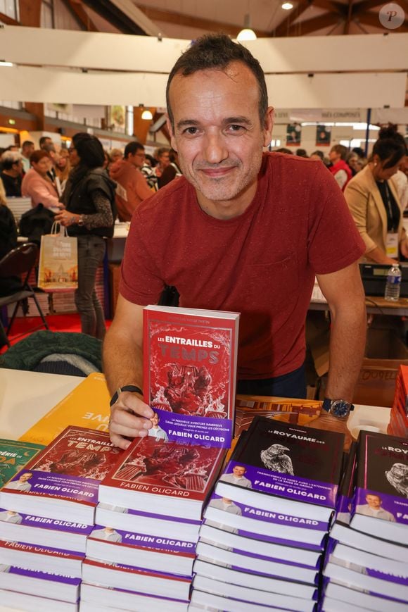 Son cobaye ? Son propre livre, "La Harpe des quatre saisons", vendu 8 euros en format poche en librairie 

Fabien Olicard à la Halle Georges Brassens à Brive-la-Gaillarde pour la Foire du Livre de Brive, le 9 novembre 2025. ©Jean-Marc LHOMER/Bestimage.