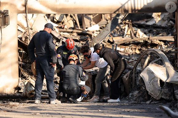 Exclusif - Des pompiers bienveillants, en déploiement dans sa rue, sont venus prêter main-forte à Laeticia Hallyday en la voyant essayer de rassembler quelques affaires  à Los Angeles, Californie, Etats-Unis, le 18 janvier 2025.
©Agence / Bestimage