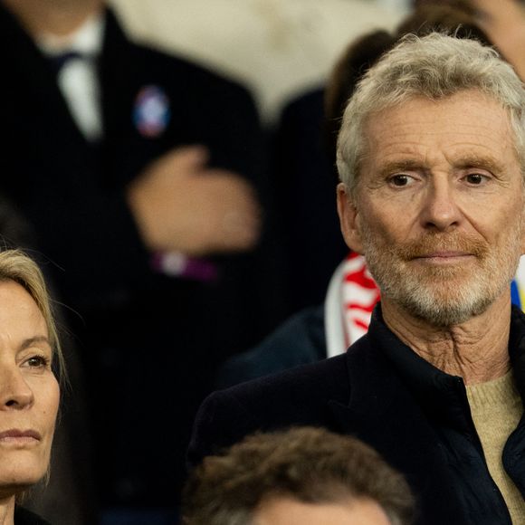 Mais c'est à quelques kilomètres de Paris qu'il vit avec sa famille.

Denis Brogniart et sa femme Hortense - Célébrités dans les tribunes du match de qualification de la Coupe du monde 2026 entre la France contre l'Ukraine (4-0) au Parc des Princes à Paris le 13 novembre 2025. © Cyril Moreau/Bestimage