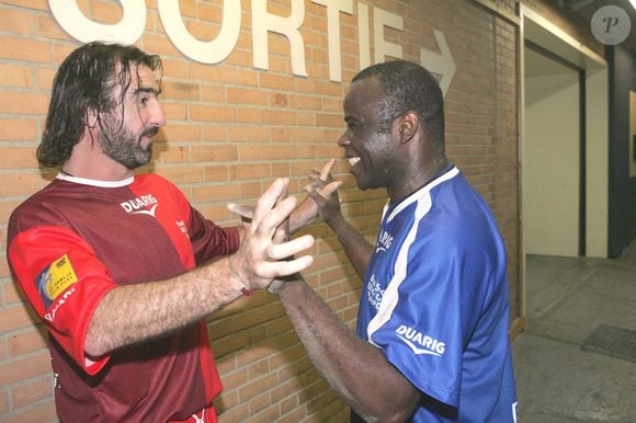 Les joueurs de football français Eric Cantona et Basile Boli lors de la Coupe de Beach Soccer de Bercy 2004 à Paris le 15 octobre 2004. Cantona est le capitaine de l'équipe européenne de beach soccer. Photo par Laurent Zabulon/ABACA.