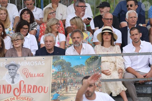 Semi-exclusif - Michel Sardou et sa femme Anne-Marie Périer, Romain Sardou et sa compagne Kym Thiriot enceinte - Michel Sardou rend hommage à son père en famille lors du premier trophée de pétanque "Fernand Sardou" à Bormes-les-Mimosas le 29 mai 2026. Le célèbre chanteur est venu en famille avec sa femme, son fils Romain avec son fils de deux ans et demi et de sa compagne enceinte de son deuxième enfant.
La première édition du Trophée Fernand Sardou est organisée du 29 au 31 mai au coeur du village de Bormes les Mimosas. Une initiative portée par Michel et son fils Romain, pour rendre hommage à leur illustre parent Fernand Sardou au travers d'un tournoi de pétanque.
En lien avec la municipalité et l'Amicale Bouliste Borméenne (ABB), un premier Trophée Fernand Sardou sera organisé avec deux grands temps forts : Le vendredi, dès 18h, un tournoi d'exhibition sera proposé et verra s'affronter 16 triplettes. Puis un concours fédéral à pétanque sera organisé le weekend et ouvert à tous les amateurs. 128 équipes seront réparties sur les sites les plus emblématiques du village, à savoir au boulodrome de la place Saint-François, mais aussi au parc Cigalou, sur le site du château et à l'ancien stade. © Franz Chavaroche/Bestimage