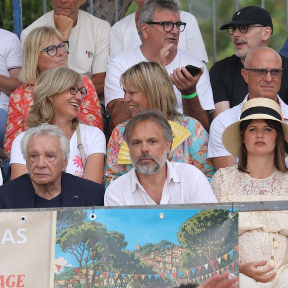 Semi-exclusif - Michel Sardou et sa femme Anne-Marie Périer, Romain Sardou et sa compagne Kym Thiriot enceinte - Michel Sardou rend hommage à son père en famille lors du premier trophée de pétanque "Fernand Sardou" à Bormes-les-Mimosas le 29 mai 2026. Le célèbre chanteur est venu en famille avec sa femme, son fils Romain avec son fils de deux ans et demi et de sa compagne enceinte de son deuxième enfant.
La première édition du Trophée Fernand Sardou est organisée du 29 au 31 mai au coeur du village de Bormes les Mimosas. Une initiative portée par Michel et son fils Romain, pour rendre hommage à leur illustre parent Fernand Sardou au travers d'un tournoi de pétanque.
En lien avec la municipalité et l'Amicale Bouliste Borméenne (ABB), un premier Trophée Fernand Sardou sera organisé avec deux grands temps forts : Le vendredi, dès 18h, un tournoi d'exhibition sera proposé et verra s'affronter 16 triplettes. Puis un concours fédéral à pétanque sera organisé le weekend et ouvert à tous les amateurs. 128 équipes seront réparties sur les sites les plus emblématiques du village, à savoir au boulodrome de la place Saint-François, mais aussi au parc Cigalou, sur le site du château et à l'ancien stade. © Franz Chavaroche/Bestimage