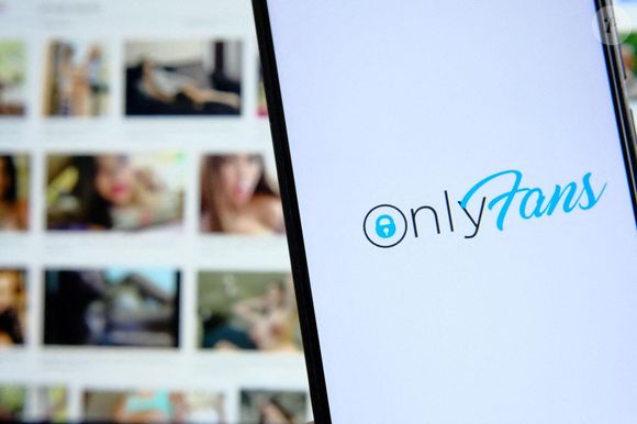 Logo de la plateforme Onlyfans sur un smartphone et photos floues de filles méconnaissables sur l'ordinateur portable en arrière-plan. Site de vente de photos explicites. Conce Photo by Alamy/ABACAPRESS.COM