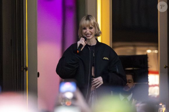 La chanteuse belge mélange habilement le style Art déco et les pièces iconiques.

La chanteuse Angèle dévoile son nouveau single "What You Want" en collaboration avec le duo électro français Justice avec une projection du clip sur la façade du Théâtre Royal de la Monnaie à Bruxelles le 25 février 2026.