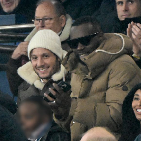 Louis Garrel, Vianney, Gims et sa femme DemDem, Jérôme Rothen - Célébrités dans les tribunes du match de Ligue 1 McDonald's opposant le Paris Saint-Germain (PSG) à Lyon (3-1) au Parc des Princes à Paris le 15 décembre 2024.