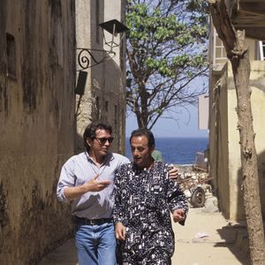 Richard Bohringer. Au Sénégal, à Gorée, l'équipe de l'émission LA GRANDE VIE et du film LES CAPRICES DU FLEUVE, Bernard GIRAUDEAU et Richard BOHRINGER déambulant dans une ruelle