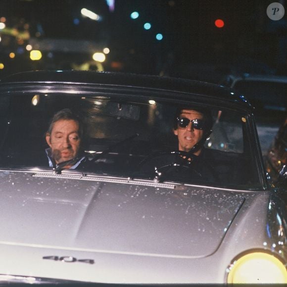 Archives - Serge Gainsbourg et Thierry Ardisson en "peugeot 404 lors de l'émission "Lunettes noires pour nuits blanches" à Paris en 1989. (AGENCE / BESTIMAGE).