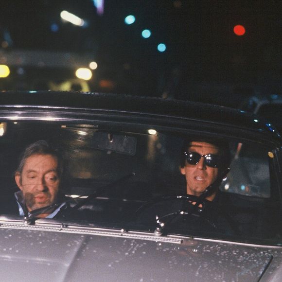 Archives - Serge Gainsbourg et Thierry Ardisson en "peugeot 404 lors de l'émission "Lunettes noires pour nuits blanches" à Paris en 1989. (AGENCE / BESTIMAGE).