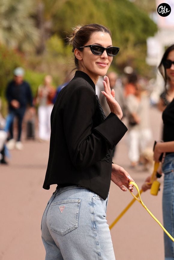 Iris Mittenaere a été aperçue en train de promener son adorable chien Calypso sur la Croisette de Cannes lors du 79e Festival de Cannes, vêtue d'un jean bleu clair à jambes larges de la marque Guess et d'une veste noire courte, le 19 mai 2026. Photo : Malu Pictures/Splash News/ABACAPRESS.COM