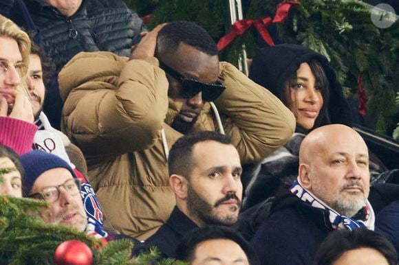 Gims et sa femme DemDem dans les tribunes du match de Ligue 1 McDonald's opposant le Paris Saint-Germain (PSG) à Lyon (3-1) au Parc des Princes à Paris le 15 décembre 2024. © Cyril Moreau/Bestimage