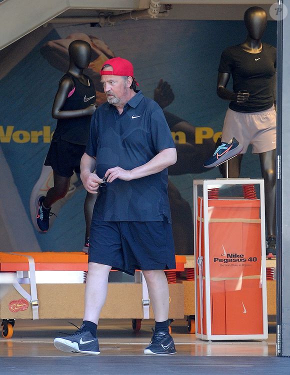 Exclusif - Matthew Perry va s'acheter des vêtements de sport Nike au centre commercial The Grove à Los Angeles, le 28 août 2023. Accompagné de son assistant, la star de "Friends" est ressorti de la boutique vêtu d "un nouveau tee-shirt et d'un short flambant neuf. Auteur d'une autobiographie à succès, l'acteur de 54 ans semble toujours fumer beaucoup à en croire la coloration orangée de son index.