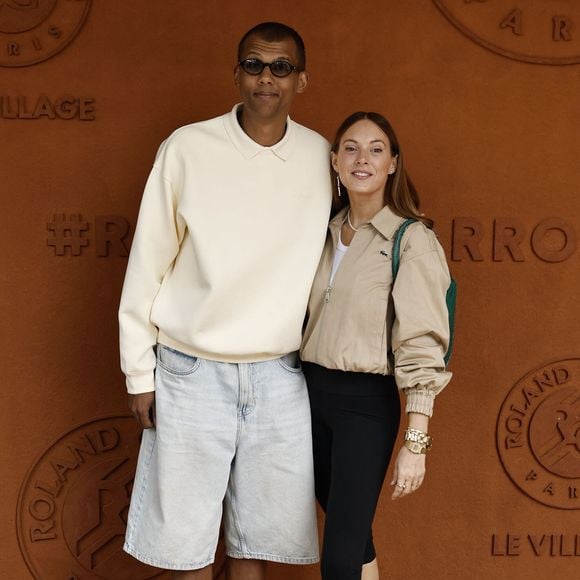 Décontracté avec ses lunettes de soleil, un pull blanc, un long short en jean bleu et des mocassins laissant apparaître ses grandes chaussettes, Stromae a pris la pose avec son épouse...

Stromae et sa femme Coralie Barbier lors des Internationaux de France de Tennis de Roland Garros 2026, à Paris, France, le 7 juin 2026. © Jacovides-Moreau/Bestimage