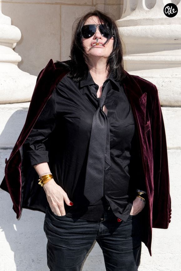 Fidèle à son aura rock et rebelle, la comédienne a opté pour un look garçonne implacable : chemise noire, cravate lâche, veste en velours jetée sur les épaules et l'éternelle cigarette à la main.

Béatrice Dalle aux arrivées du deuxième défilé de mode Saint Laurent Prêt à Porter Collection Homme Printemps/Été 2027 lors de la Fashion Week de Paris à la Bourse de Commerce - Pinault Collection, à Paris, France, le 23 juion 2026. © Olivier Borde/Bestimage