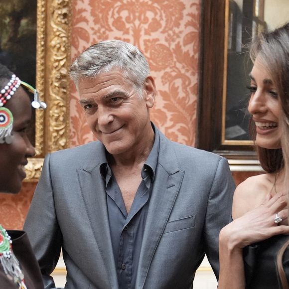La raison ? L'absence de cravate sur son costume gris, symbole de désinvolture et de manque de respect pour beaucoup apparemment...

George Clooney et Amal Clooney lors de la réception en l'honneur des lauréats des King's Trust Awards au palais de Buckingham le 25 juin 2025  Stefan Rousseau/WPA-Pool/Bestimage
