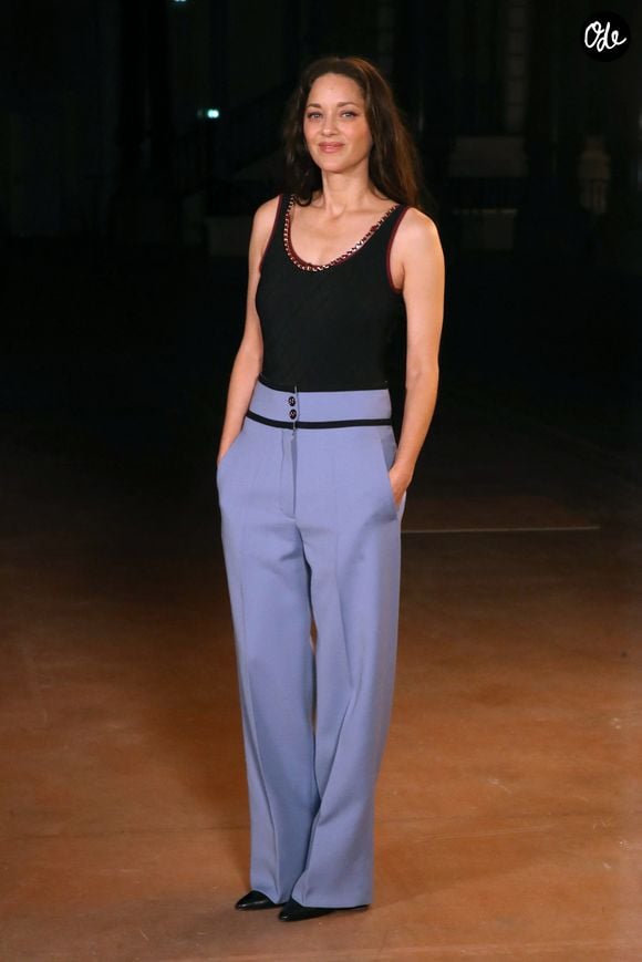 Marion Cotillard, régulièrement habillée par Chanel, avait choisi un pantalon bleu pastel à la coupe large, associé à un body noir ajusté et dos nu.

Marion Cotillard - Célébrités au Défilé Chanel, Collection Prêt-à-porter Printemps / Eté 2027 dans le cadre de la Fashion Week de Paris, France, le 05 Octobre 2026. © Bertrand Rindoff / Bestimage