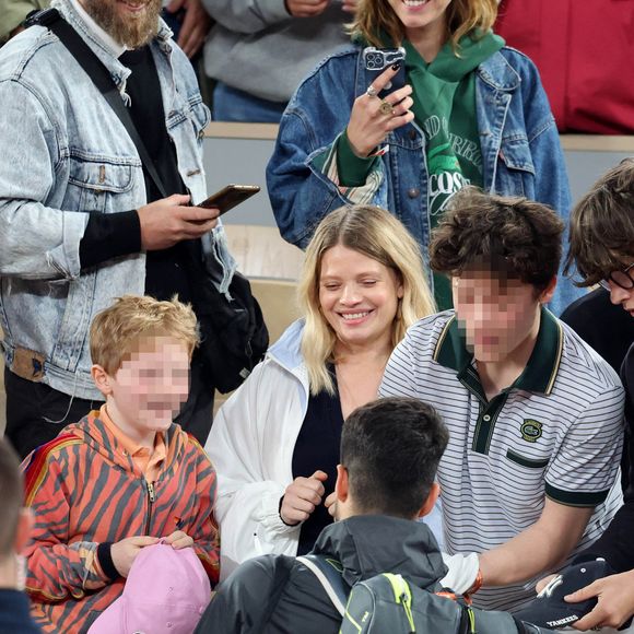 Roman et Aliocha Haroche voient Carlos Alcaraz dédicacer leurs casquettes sous le regard de leurs parents, Mélanie Thierry et son compagnon Raphaël - Les célébrités dans les tribunes des Internationaux de France de tennis de Roland Garros 2024 à Paris, le 29 mai 2024. 
© Jacovides / Moreau / Bestimage