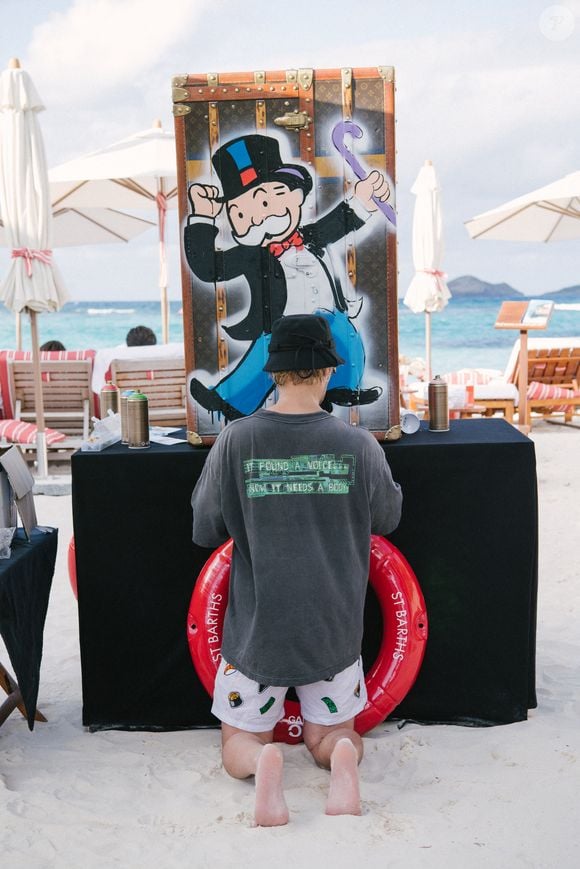 Aujourd'hui, il perpétue cette promesse avec 170 artisans qui travaillent juste à côté de la maison, là où le "sur-mesure" reste la règle d'or.

Exclusif - Alec Monopoly customise une malle Louis Vuitton qui sera vendue aux enchères pour une oeuvre caritative lors de la soirée The Saint Barths Dinner by Gala One à l'Eden Rock à Saint-Barthélémy qui se tiendra le 29 décembre 2024.
© Tiziano da Silva / SamDelpech / Bestimage