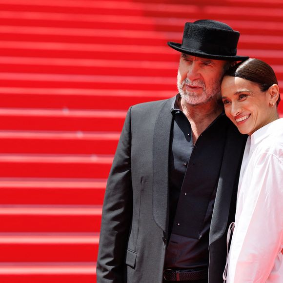 Très affectueux l'un envers l'autre, le couple a pris la pose dans des tenues parfaitement contrastées : un total look noir surmonté d'un chapeau pour l'ancien footballeur, et une robe blanche immaculée pour son épouse.

Eric Cantona et sa femme Rachida Brakni - Montée des marches du film " Soudain " lors du 79ème Festival International du Film de Cannes, le 15 mai 2026. © Jacovides-Moreau / Bestimage